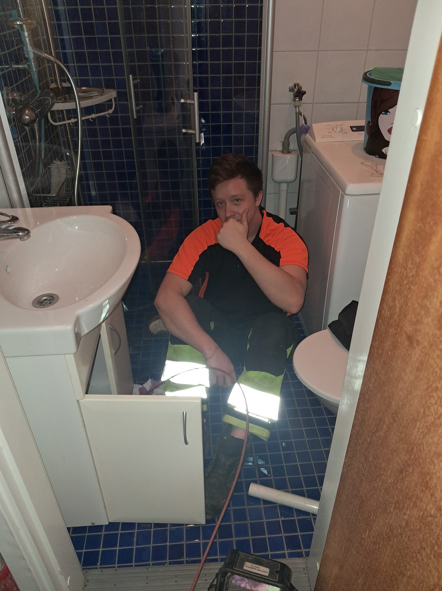 En anställd på RL Avlopp sitter och undersöker ett handfat. 